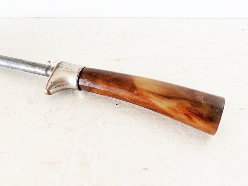 May include: A vintage metal and brown plastic steak knife with a silver handle.