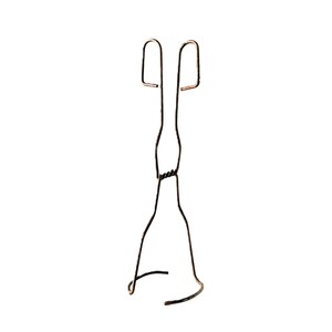 May include: A vintage-style metal crucible tong featuring a dark, oxidised copper-toned finish. The tool consists of two long, slender wire arms that cross at a central twisted pivot point, ending in two rectangular finger loops and a curved base.