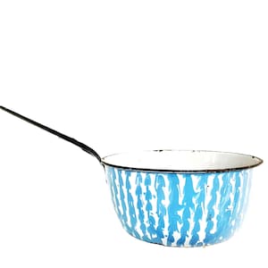 May include: A round enamel saucepan featuring a white interior and a blue and white marbled pattern on the exterior. The pan has a long, thin, black metal handle extending from the side and a black rim around the top edge of the basin.