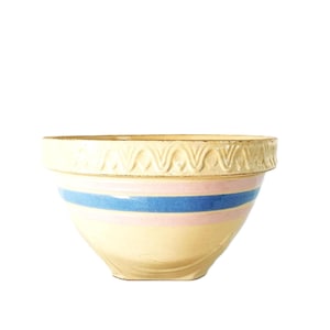 Puede incluir: Cuenco de cerámica color crema con rayas azules y rosas. El cuenco tiene un borde decorativo con un patrón repetido. Un artículo de cocina clásico.