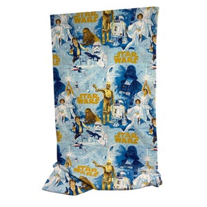 May include: A light blue Star Wars-themed fabric featuring various characters like Darth Vader, C-3PO, and R2-D2. The fabric has a repeating pattern with the words "Star Wars" in gold. The overall design is a vintage style.