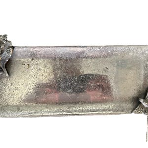 May include: A rectangular, silver-colored tray with a textured surface. The tray is decorated with a rose and leaves on one end and a butterfly on the other. The tray is likely made of metal.