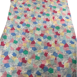 May include: A colorful patchwork quilt with a repeating pattern of geometric shapes in shades of pink, blue, green, and yellow. The quilt has a light gray background with a subtle plaid design. The quilt is made of fabric.