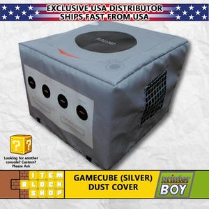 May include: A gray dust cover for a Nintendo GameCube console. The cover has a printed image of the GameCube console and the text "GAMECUBE (SILVER) DUST COVER".