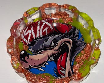 Cenicero artesanal de resina epoxi con diseño de lobo y copos verdes y cobre.
