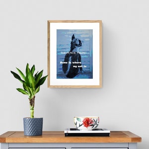 May include: A framed print with a blue and white abstract background featuring a black and white cat. The text "THE PENCIL VIKING" and "Home is where my cat is" is printed on the print.