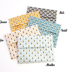 Op de afbeelding: Vijf stoffen cadeauzakken met een geometrisch waaiervormig patroon in verschillende kleuren, waaronder geel, roze, blauw, groen en zwart. De zakken zijn gelabeld met de kleuren: Jaune, Rose, Foret, Menthe en Noir.