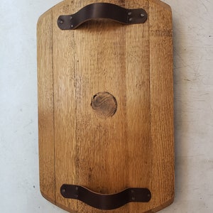 May include: A wooden serving tray with two leather handles. The tray is made from reclaimed wood and has a natural finish.