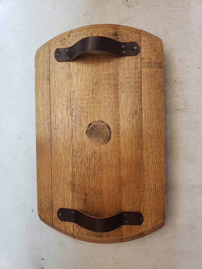 May include: A wooden serving tray with two leather handles. The tray is made from reclaimed wood and has a natural finish.