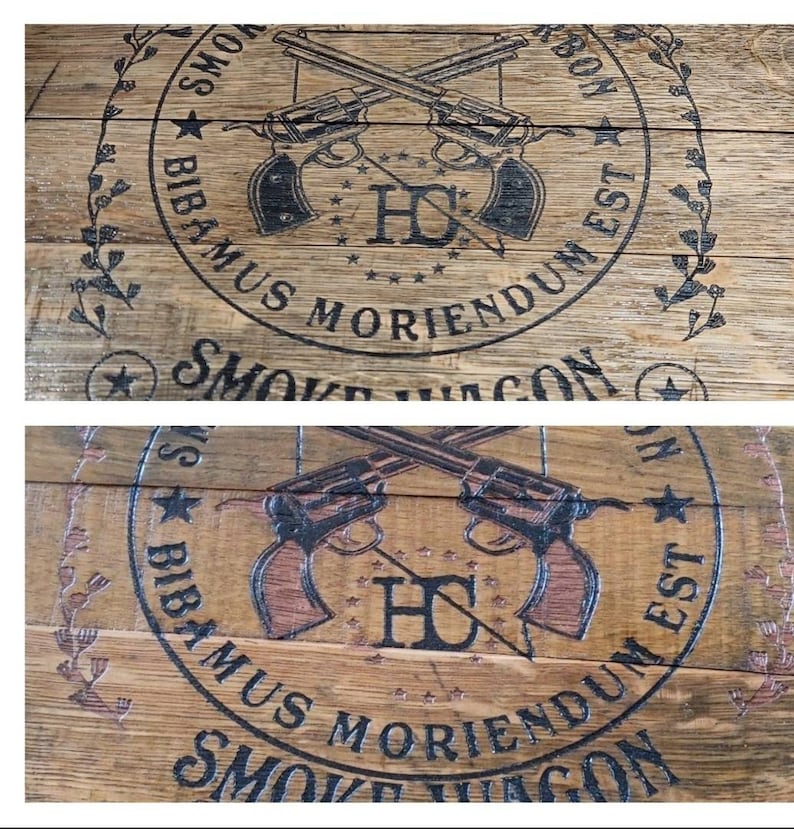 May include: Close-up of a wooden barrel with a black and white logo. The logo features two crossed revolvers, the letters "HC", and the text "YOWS BIBAMUS MORIENDUM EST SMOKE VAGON".