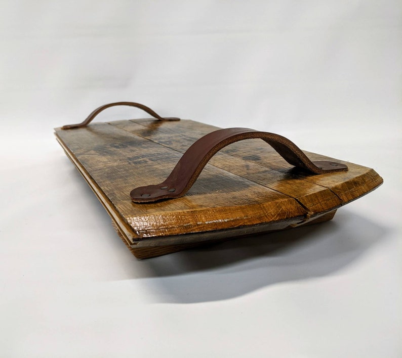May include: A wooden serving tray with two leather handles. The tray is made from reclaimed wood and has a rustic look.
