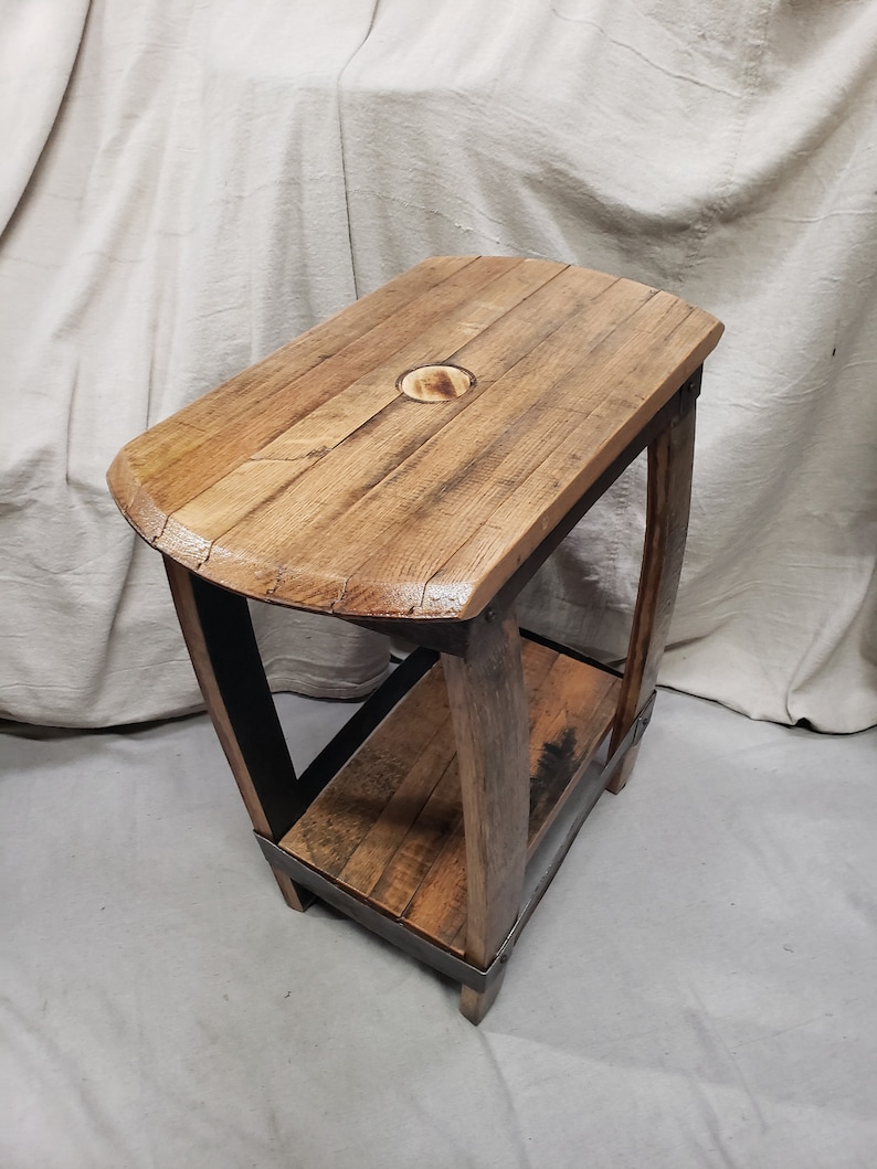 Pu&ograve; includere: Un tavolino rustico in legno con piano rettangolare e ripiano inferiore. Il tavolo &egrave; costruito con legno di recupero con venature visibili e finitura naturale. Le gambe sono sostenute da fasce metalliche.