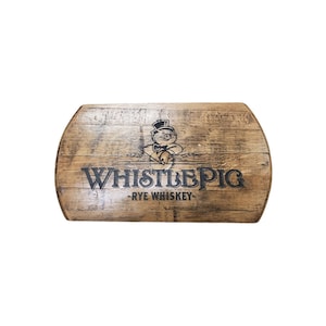 Pu&ograve; includere: Un'insegna in legno con la scritta "WHISTLEPIG RYE WHISKEY" in lettere nere. L'insegna presenta un maiale dei cartoni animati con un cappello a cilindro e una bottiglia. L'insegna &egrave; ricavata da una sezione di botte.