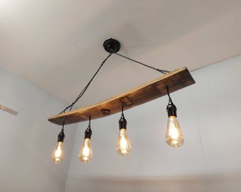 May include: A rustic wooden chandelier with four Edison bulbs hanging from a black chain. The chandelier is made from a reclaimed wine barrel stave.