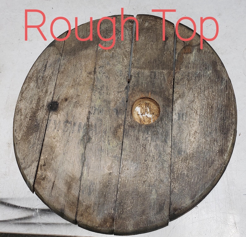 May include: Rough Top is written on a wooden round disc with a hole in the center. The disc is made of wood planks and has a rustic, weathered look.