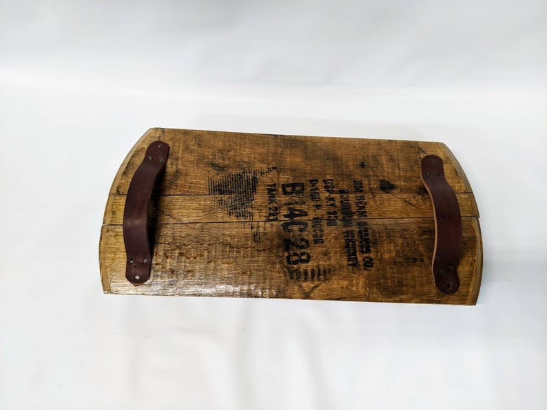 May include: A wooden serving tray made from a repurposed whiskey barrel with two leather handles. The barrel has the text "WM.  REAMS & SONS, INC.  LOUISVILLE, KY.  DIST. BY  NATIONAL DISTILLERS PRODUCTS CO.  P.O. BOX 1230  N.Y.C.  TANK 221  B14C28" printed on it.
