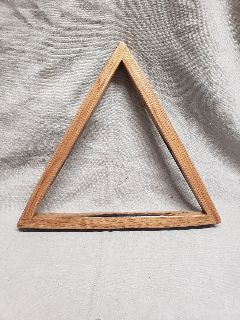 May include: A wooden triangle rack for pool balls. The rack is made of light brown wood with a dark brown stain. The rack is designed to hold the balls in a triangular shape.