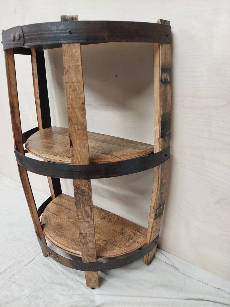 May include: A three-tiered shelf unit made from reclaimed wood barrel staves and metal bands. The shelves are curved and the unit has a rustic, industrial look.