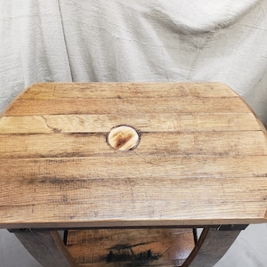 Pu&ograve; includere: Un tavolino rustico in legno con piano curvo in legno di recupero. Il piano presenta un inserto circolare ed &egrave; sostenuto da un telaio in metallo. Le dimensioni del tavolo sono di circa 76 cm di lunghezza, 46 cm di larghezza e 51 cm di altezza.