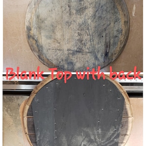May include: A round wooden top with a natural wood finish. The top is blank and ready to be decorated. The back of the top is painted black.