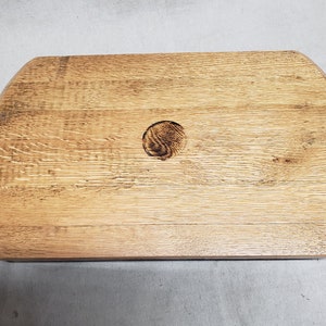 May include: A natural wood serving tray with a round hole in the center. The tray has a rustic, weathered look and is perfect for serving snacks or drinks.