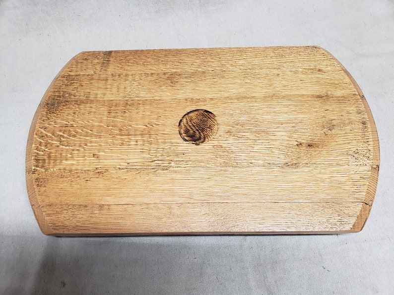 May include: A natural wood serving tray with a round hole in the center. The tray has a rustic, weathered look and is perfect for serving snacks or drinks.