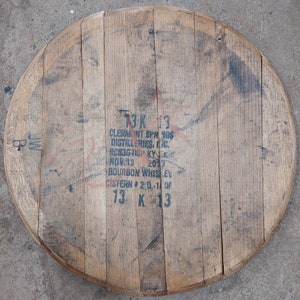 May include: A wooden barrel head with the text "3K 13 Clermont Springs Distilleries, Inc.  #C5336-13P KY-31 NOV.13 2013 Bourbon Whiskey Cistern #2 D.-1 of 13 K 13" printed on it.