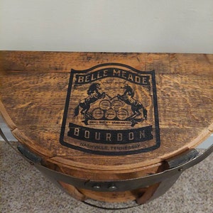 May include: A wooden barrel with a metal band, featuring a black and white label that reads "Belle Meade Bourbon, Small Batch - Handcrafted, Nashville, Tennessee".