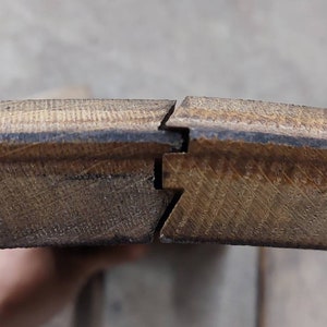 May include: Close-up of two pieces of wood flooring with a tongue and groove joint. The wood is a light brown color and has a natural grain pattern.