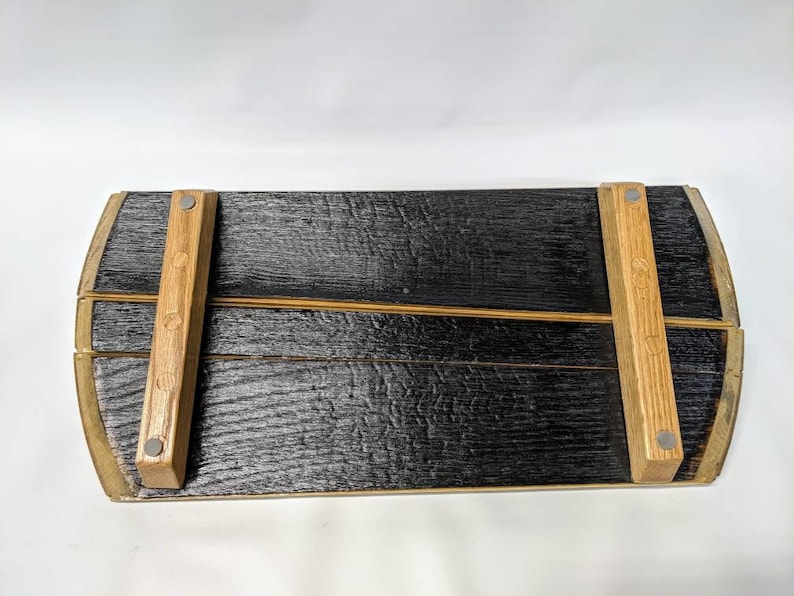 May include: A wooden serving tray made from reclaimed barrel staves. The tray has a black charred finish and is supported by two wooden legs attached with metal screws.