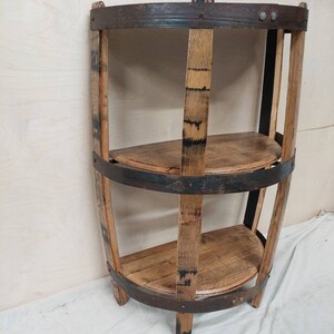 May include: A three-tiered shelf made from reclaimed wood barrel staves with metal bands. The shelf is curved and has a rustic, industrial look.
