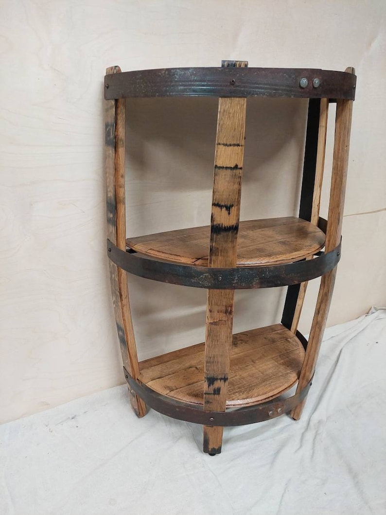 May include: A three-tiered shelf made from reclaimed wood barrel staves with metal bands. The shelf is curved and has a rustic, industrial look.