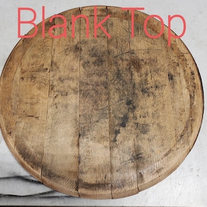 May include: A round wooden top, likely from a barrel, with a natural wood finish and visible grain. The top is slightly weathered and has a few dark spots.