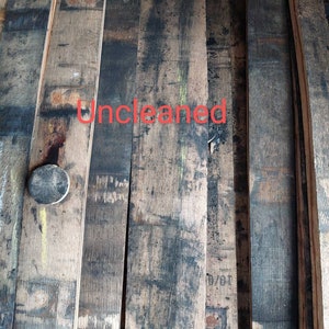 May include: Close-up of several wooden planks, likely from a barrel, showing the natural grain and dark stains. The planks are stacked and appear to be uncleaned. The text "Uncleaned" is written in red on the planks.