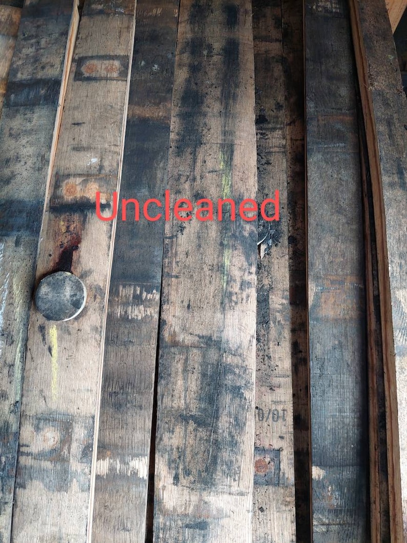 May include: Close-up of several wooden planks, likely from a barrel, showing the natural grain and dark stains. The planks are stacked and appear to be uncleaned. The text "Uncleaned" is written in red on the planks.