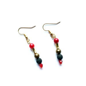 Könnte beinhalten: Ein Paar goldene Ohrhänger mit roten, schwarzen und goldenen Perlen. Die Ohrringe haben ein schlichtes Design und sind perfekt für den Alltag.