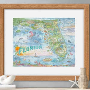 Könnte beinhalten: Aquarellkarte von Florida in einem Holzrahmen. Die Karte zeigt Illustrationen von Meereslebewesen, Sehenswürdigkeiten und das Wort "Florida" in einer stilisierten Schriftart. Das Kunstwerk wird auf einer weißen Oberfläche mit dekorativen Elementen präsentiert.