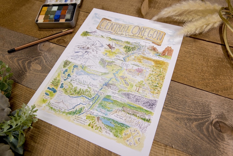 K&ouml;nnte beinhalten: Eine handgezeichnete Aquarellkarte von Central Oregon mit den Cascade Mountains, Fl&uuml;ssen, Seen und St&auml;dten. Die Karte tr&auml;gt den Titel "Central Oregon, A Piece of Wonderland".