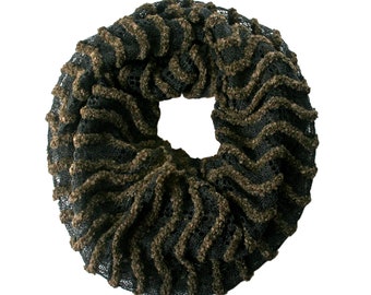 May include: A black and brown infinity scarf with a textured, wavy design. The scarf is circular, with a central opening, and features a combination of black netting and brown, fuzzy detailing. The overall aesthetic is cozy and stylish.