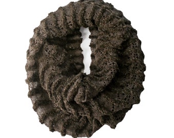 May include: A brown infinity scarf with an open, lacy weave. The scarf is made from a soft, textured material and is designed to be worn around the neck. The colour is a dark, earthy brown. The open weave gives it a delicate, airy appearance. The scarf is circular.