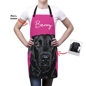 May include: Pink apron with a black dog's face on it. The dog's name is "Benny" in white cursive writing.