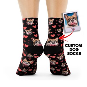 May include: A pair of black ankle socks with a repeating pattern of pink hearts and a dog's face. The dog's face is the same on each sock. The socks are shown on a model's feet. The text "CUSTOM DOG SOCKS" is visible in the image.