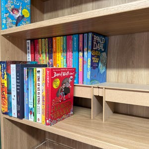 May include: A wooden bookshelf filled with colorful books. Titles include "Boy", "Charlie", and "Gangsta Granny". The books are arranged on multiple shelves, creating a visually appealing display for a home library.