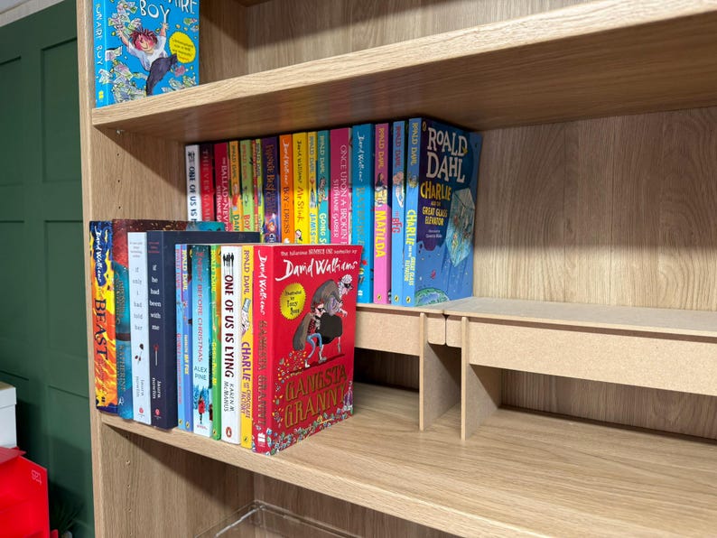 May include: A wooden bookshelf filled with colorful books. Titles include "Boy", "Charlie", and "Gangsta Granny". The books are arranged on multiple shelves, creating a visually appealing display for a home library.