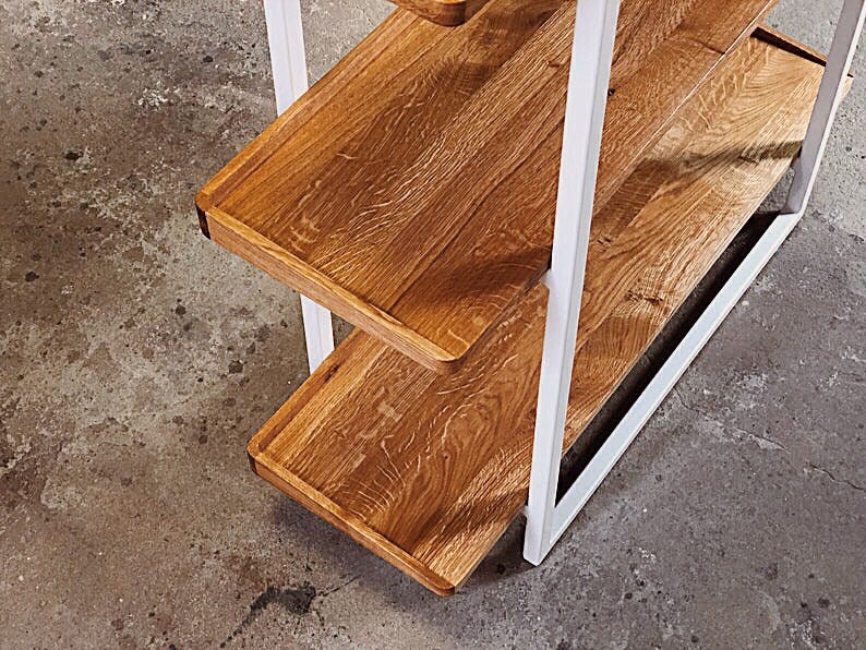 Puede incluir: Estanter&iacute;a de metal blanco con tres estantes de madera. Los estantes son de madera natural con un acabado marr&oacute;n claro.
