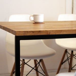 May include: A wooden table with a black metal frame and white chairs. The table has a natural wood finish and the chairs have a simple design.