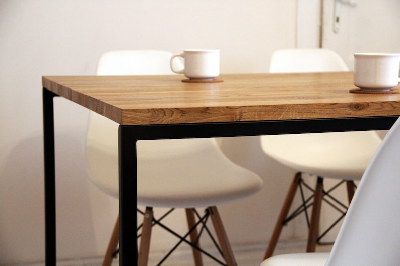 May include: A wooden table with a black metal frame and white chairs. The table has a natural wood finish and the chairs have a simple design.