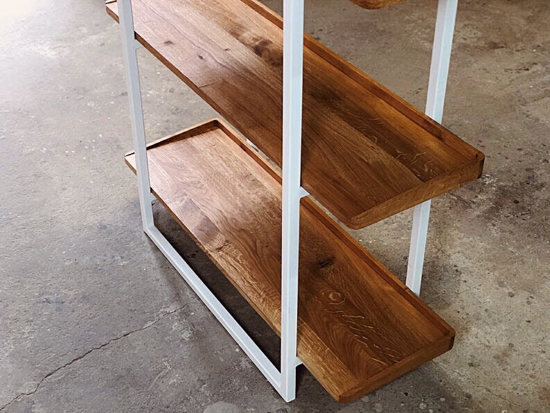 Puede incluir: Una estanter&iacute;a de metal blanco con tres estantes de madera. Los estantes son de madera natural con un acabado marr&oacute;n claro. El marco de metal est&aacute; pintado de blanco.
