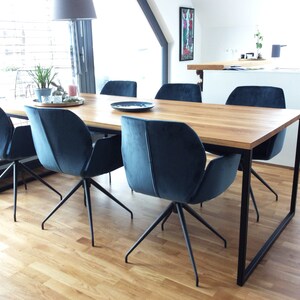 May include: A wooden dining table with a black metal frame and six blue velvet chairs. The table is set with a plate and a glass on each chair.