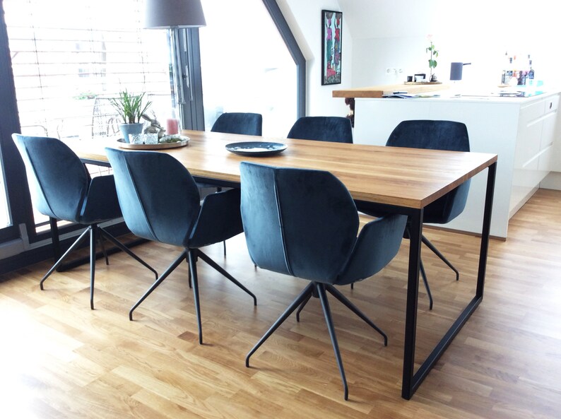 May include: A wooden dining table with a black metal frame and six blue velvet chairs. The table is set with a plate and a glass on each chair.
